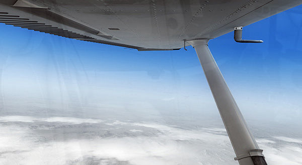Aerial view of clouds and blue sky from inside an airplane window.