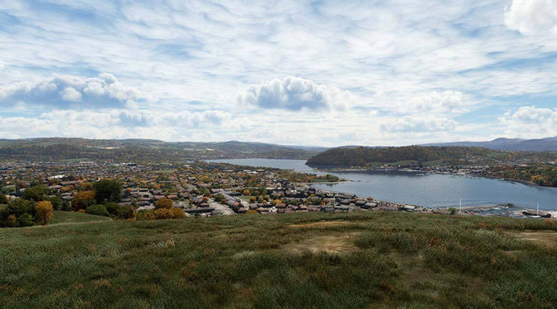 Scenic view of city, lake, and mountain in the distance.