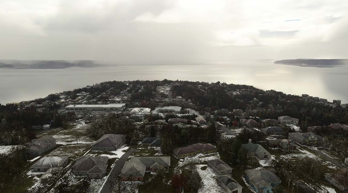Aerial shot of neighborhood covered in snow, with houses and trees.