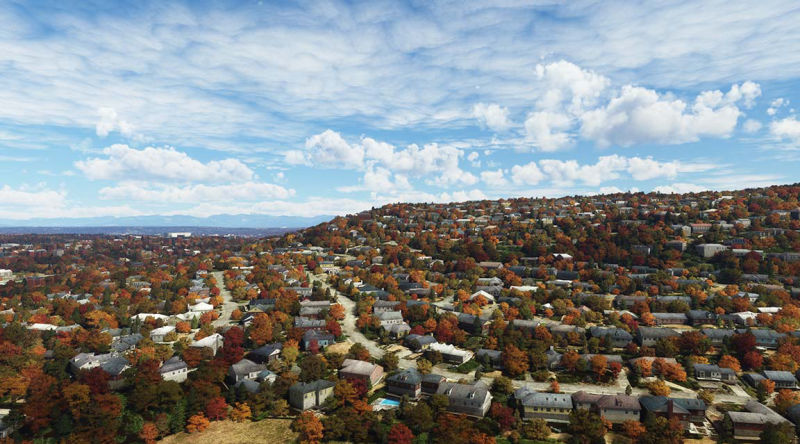 Aerial view of a fall neighborhood with colorful trees, houses, and streets.
