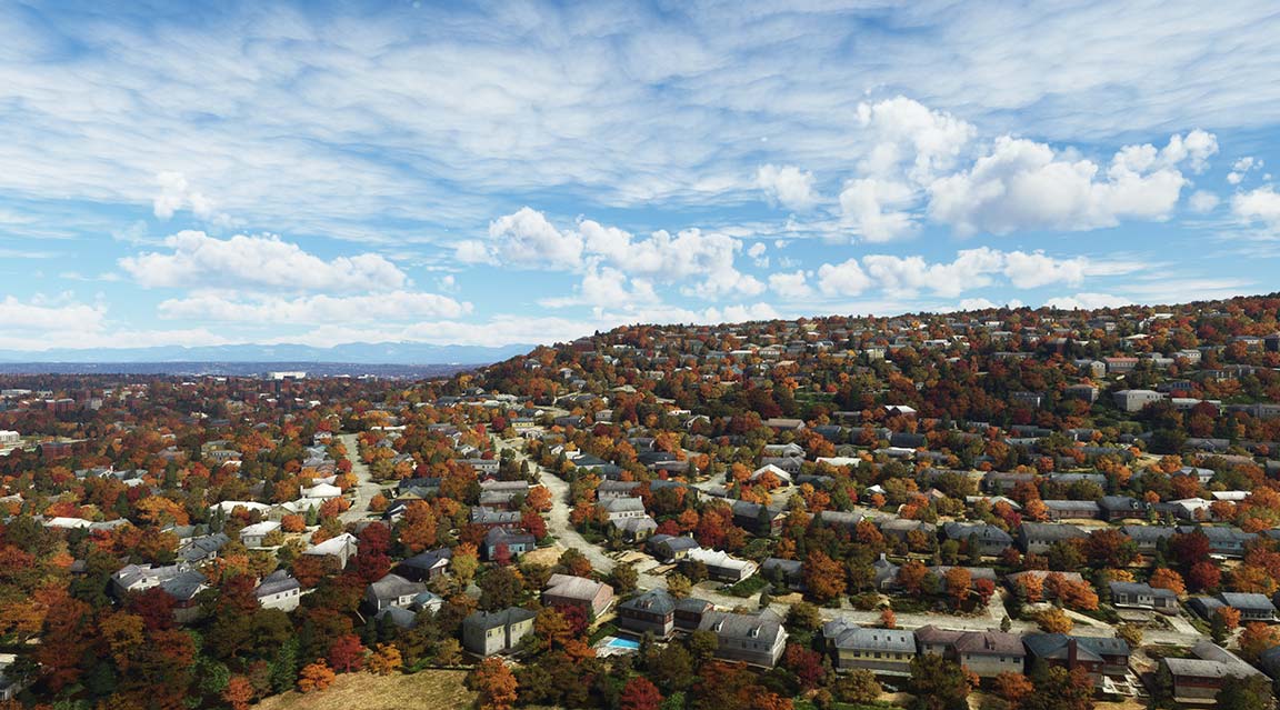Aerial view of a fall neighborhood with colorful trees, houses, and streets.