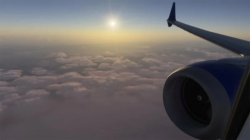 Airliner wing and engine against the sun above a cloud deck, REX Atmos CORE atmospheric scattering in Microsoft Flight Simulator 2024