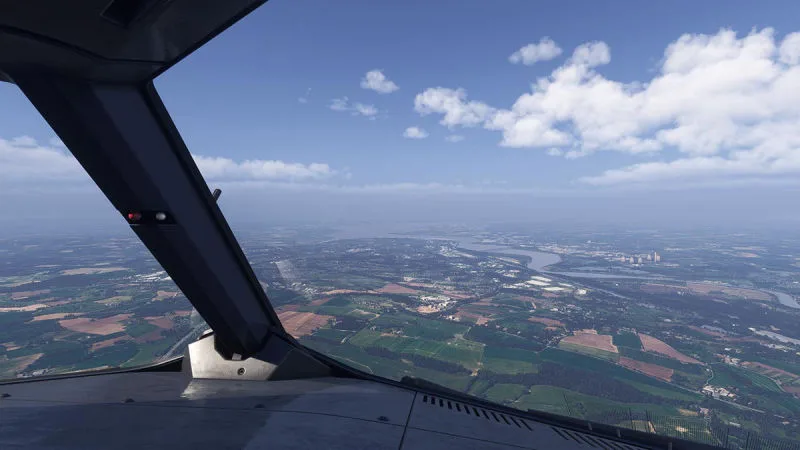 Cockpit view over green fields and a winding river under puffy cumulus clouds, REX Atmos CORE in Microsoft Flight Simulator 2024