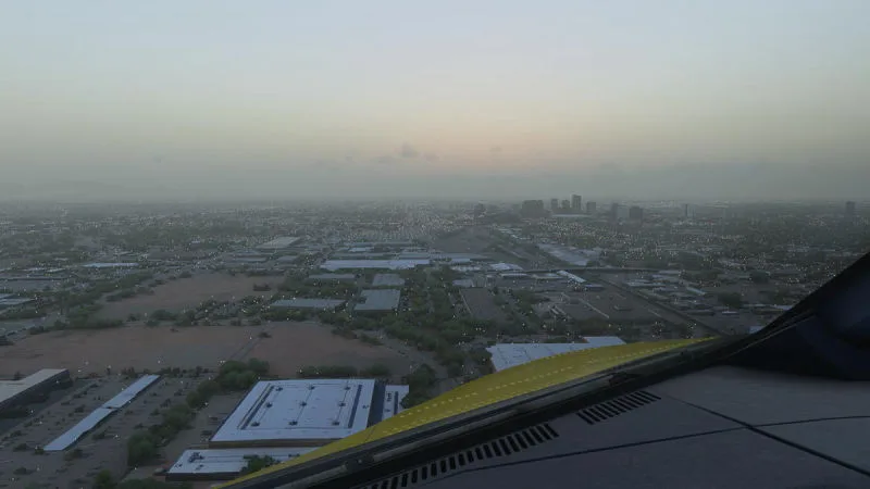 Wing view descending over a sprawling desert city at dusk, REX Atmos CORE in Microsoft Flight Simulator 2024