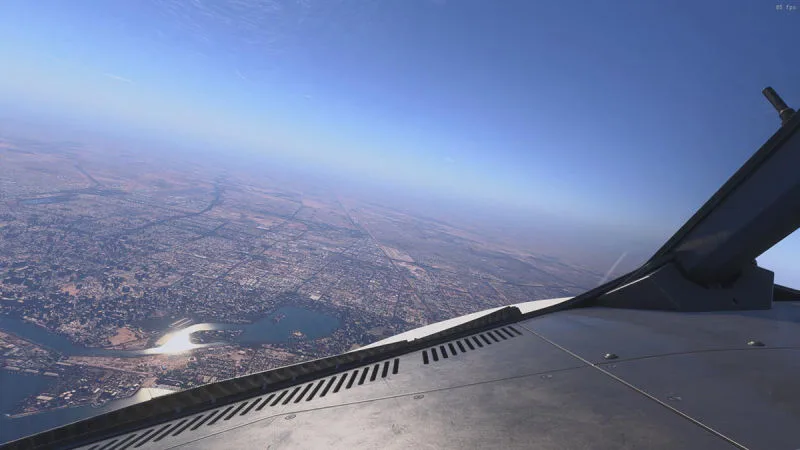 High-altitude wing view over a desert city and river, REX Atmos CORE in Microsoft Flight Simulator 2024