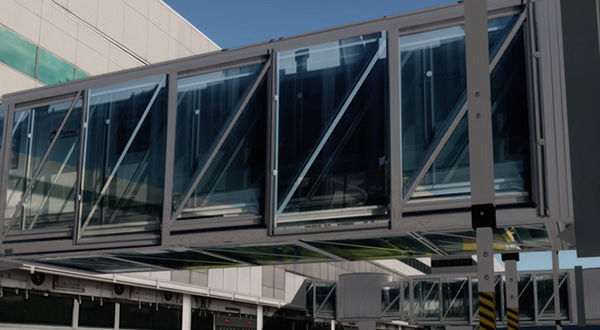 A modern airport terminal with a jetway, featuring a large metal building with glass windows.
