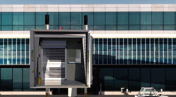 A large airport terminal with a jetway, a large door, and a large truck.