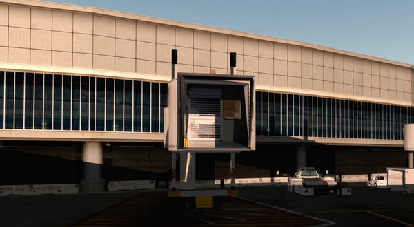 Airport terminal with jetway, featuring a large white building.