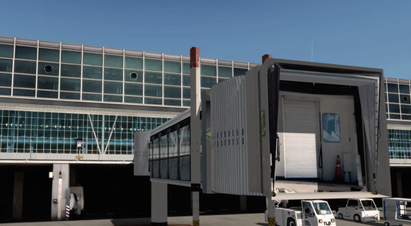 A large airport terminal with a jetway, a massive door, and a truck parked outside.