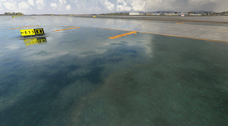 A large airport runway with a yellow sign in the foreground.