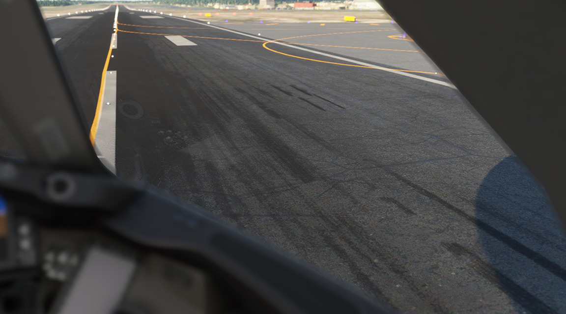 A view from inside a plane on the runway, showing the tarmac and airport buildings in the background.