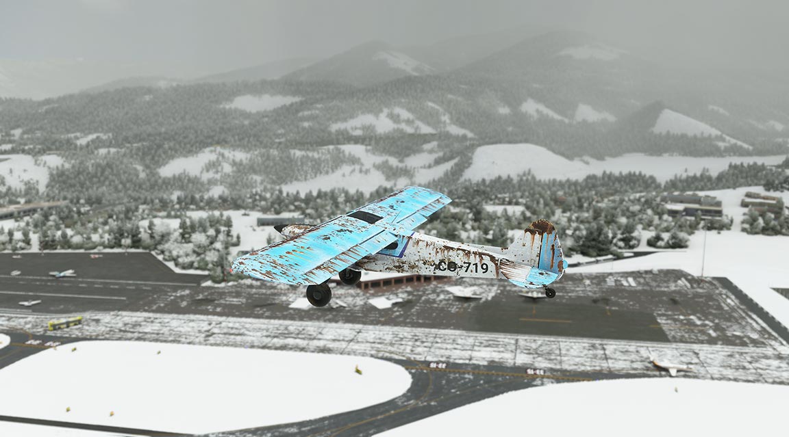 Aircraft on snowy tarmac with mountain backdrop.