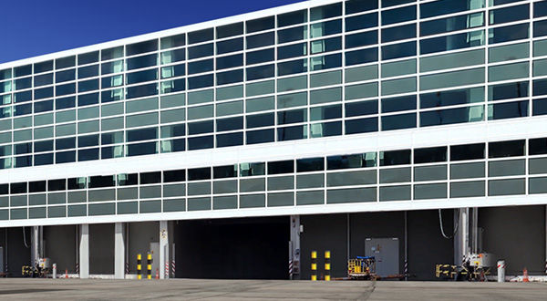 A bustling airport terminal with a prominent large building nearby.