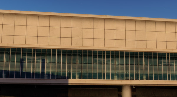 Modern airport terminal building with a large window overlooking the runway.